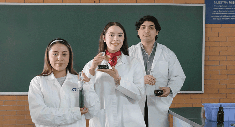 Three diverse students in lab coats holding scientific beakers with liquids.
