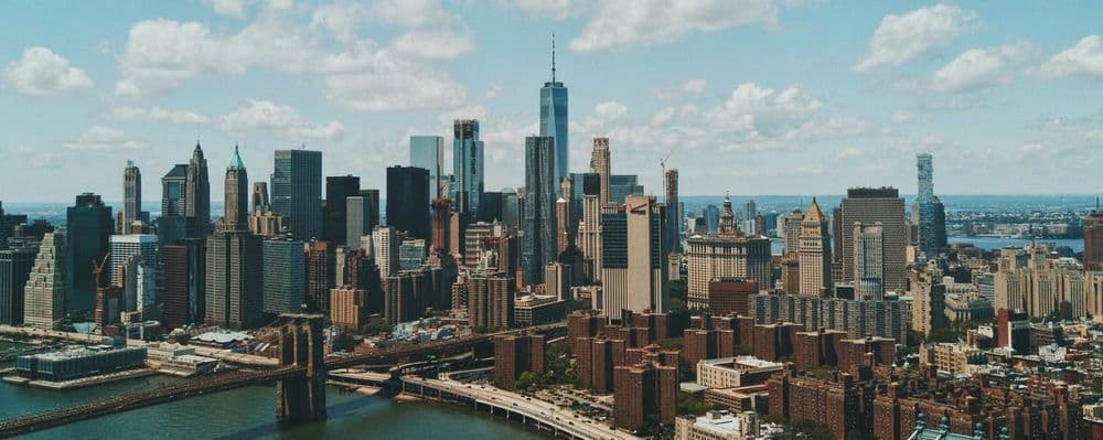 Panoramic view of the New York City skyline featuring One World Trade Center and Brooklyn Bridge.