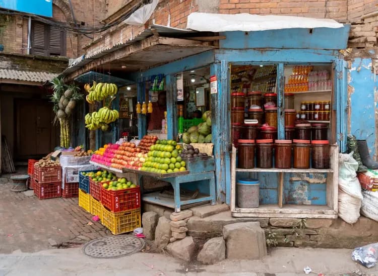 A rustic blue street stall overflows with fresh fruits, vegetables, and jars of preserves.